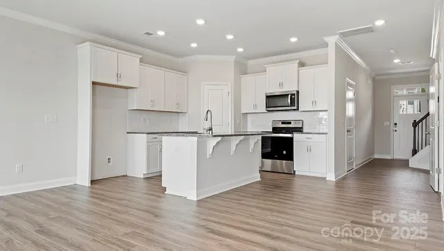 an open kitchen with white cabinets and stainless steel appliances