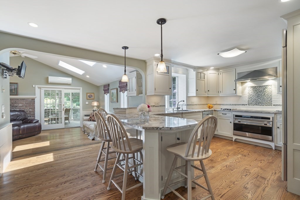 57 Surrey Lane Boxford, MA 01921 - Photo 9 of 42 a kitchen with stainless steel appliances kitchen island granite countertop a stove top oven a sink a dining table and chairs with wooden floor