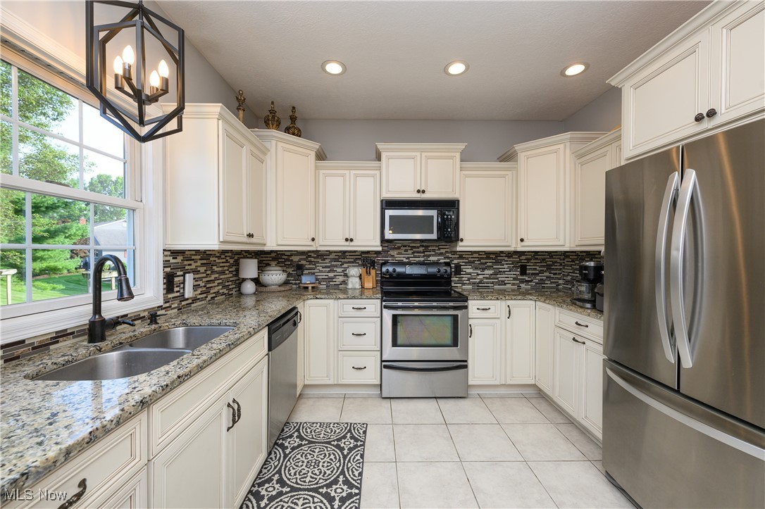 Bright and airy Kitchen featuring pendant lighting, stainless steel appliances, backsplash, light tile patterned floors