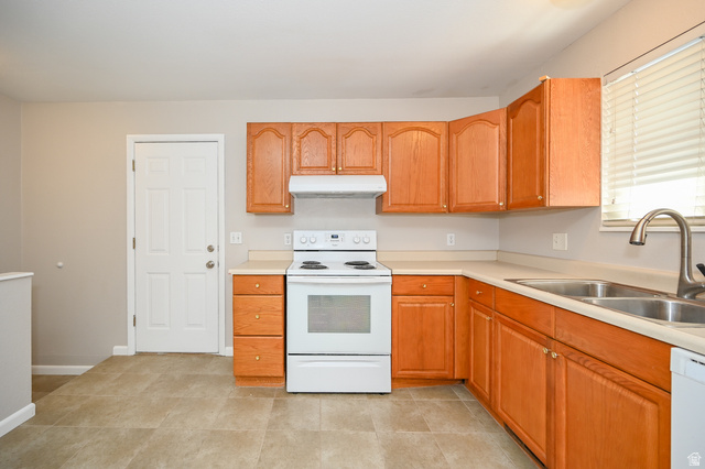 916 Vics Road, Unit 2 Sandy, UT 84094 - Photo 8 of 23 Kitchen featuring wood-finish cabinetry with silver-tone hardware, a white electric range with coordinating range hood, a double basin stainless steel sink with a gooseneck faucet, light-toned countertops, and neutral tile flooring