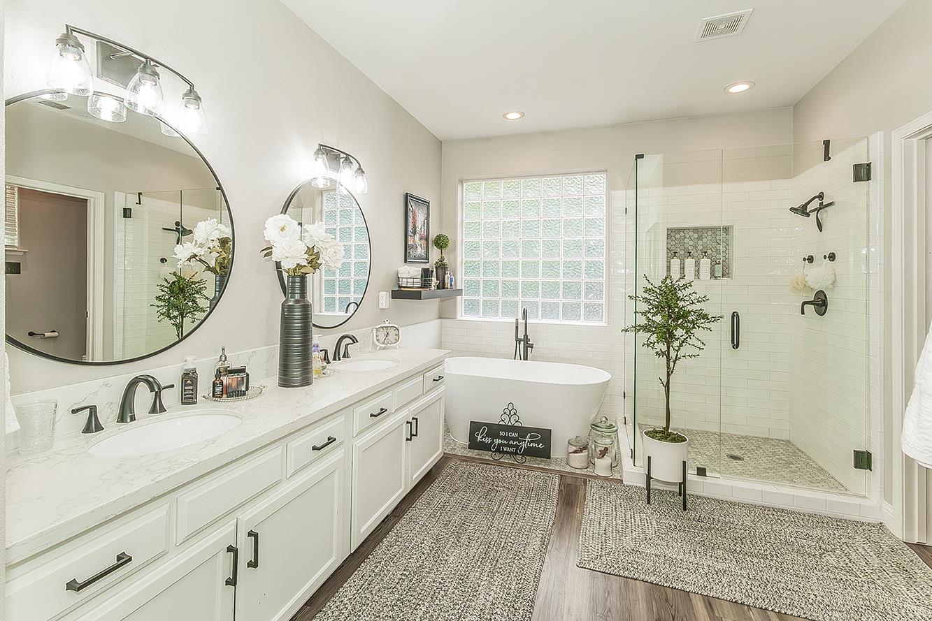 1175 Applegate Avenue Clovis, CA 93611 - Photo 24 of 65 a bathroom with double vanity sinks a large mirror and a bathtub