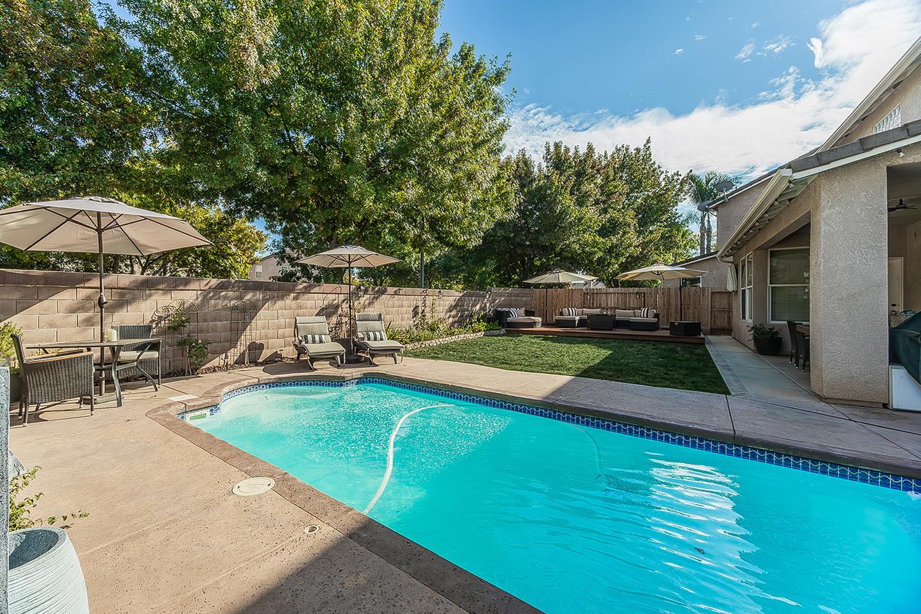 1175 Applegate Avenue Clovis, CA 93611 - Photo 38 of 65 a view of a swimming pool with lawn chairs under an umbrella