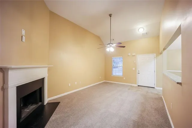 a view of an empty room with chandelier fan and fire place