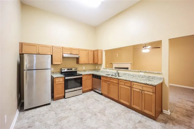 a kitchen with granite countertop a refrigerator and a stove top oven