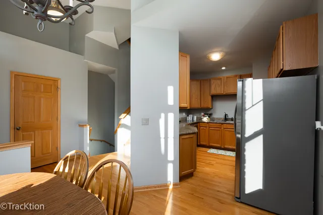 a kitchen with stainless steel appliances granite countertop a refrigerator a stove a sink and a dining table with wooden floor