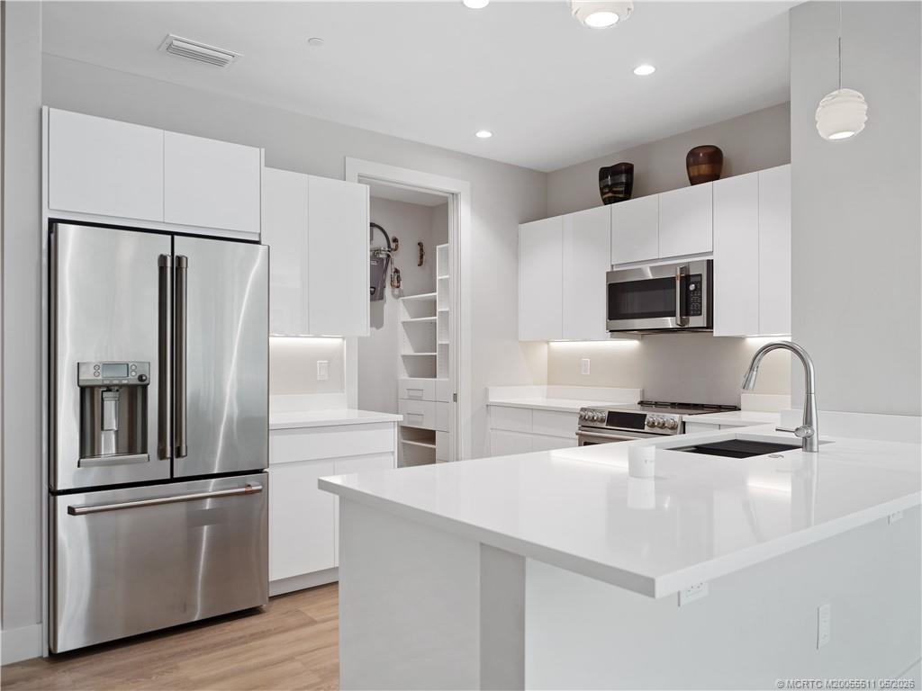 41 Southwest Seminole Street, Unit 208 Stuart, FL 34994 - Photo 5 of 46 a kitchen with stainless steel appliances a refrigerator stove microwave and sink