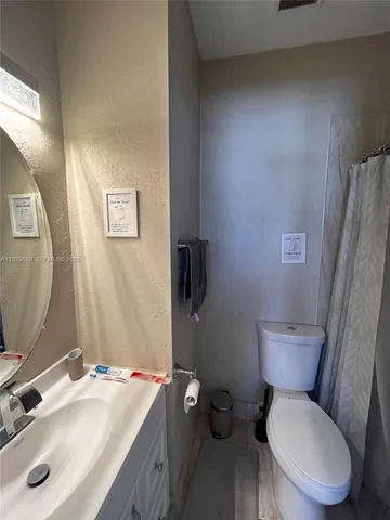 a bathroom with a granite countertop toilet sink and mirror