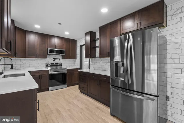 a kitchen with kitchen island a refrigerator wooden cabinets and stainless steel appliances