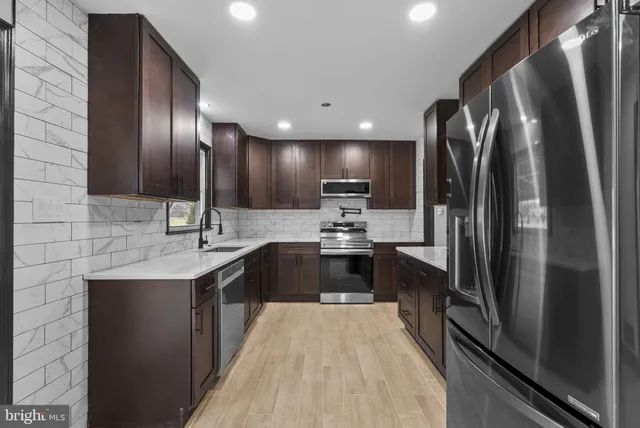 a large kitchen with a large counter top a sink and stainless steel appliances