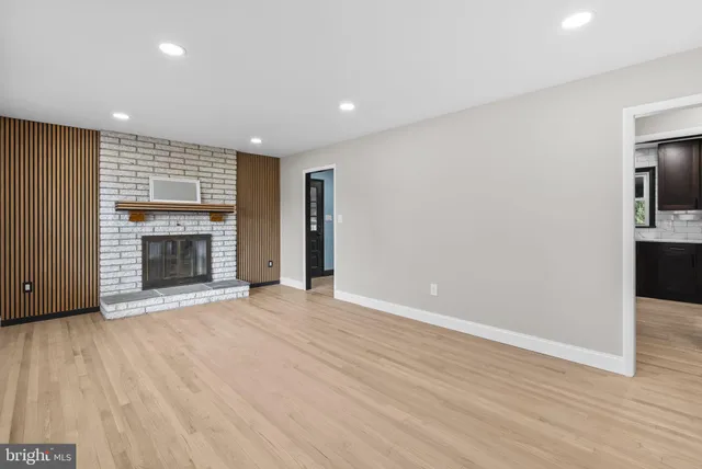 an empty room with wooden floor fireplace and windows