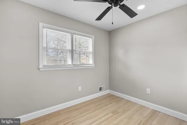 an empty room with a window and a fan