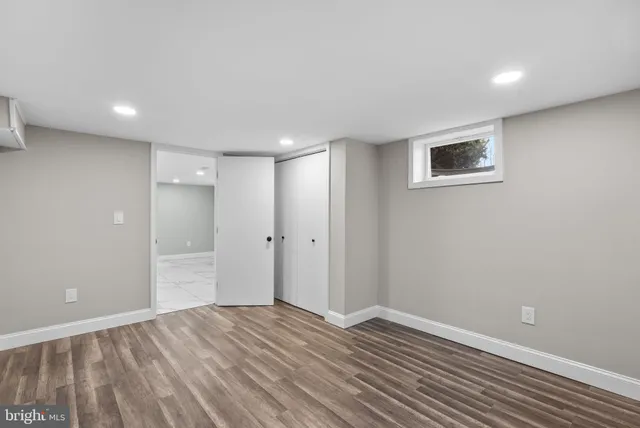 a view of an empty room with wooden floor and closet
