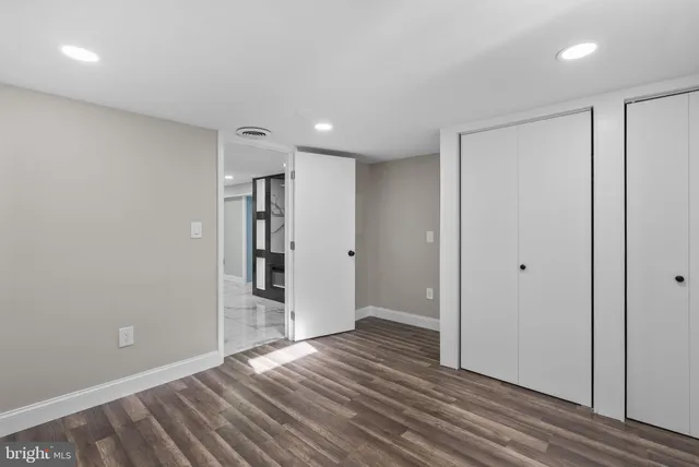 a view of an empty room with wooden floor and closet