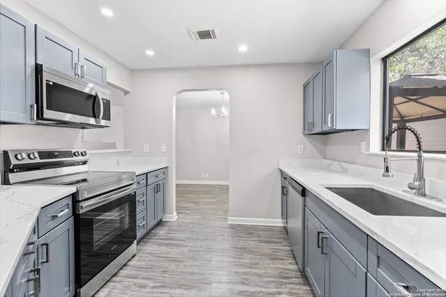 a kitchen with stainless steel appliances granite countertop a sink stove microwave and refrigerator