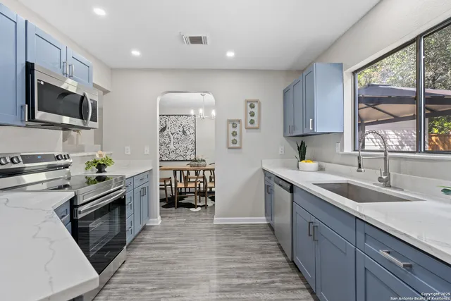 a kitchen with granite countertop a sink stove and cabinets