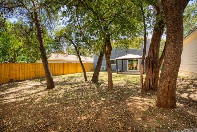 a view of a house with backyard and trees