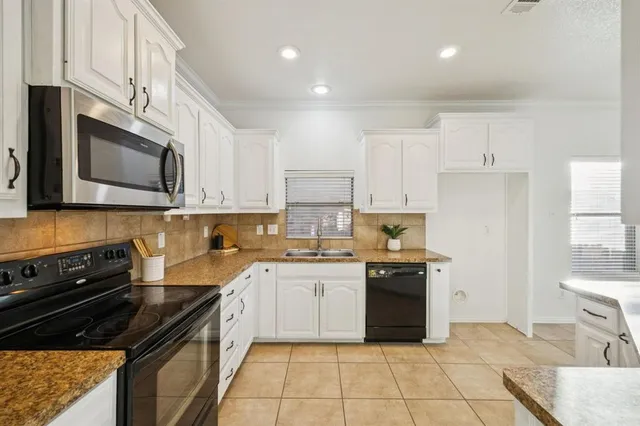 a kitchen with stainless steel appliances granite countertop a stove top oven a sink dishwasher and a refrigerator