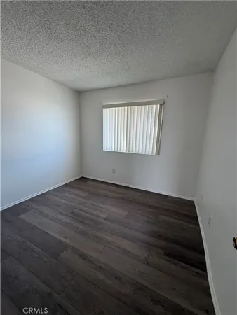 a view of an empty room with wooden floor and window