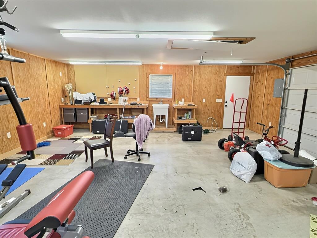 313 East River Oaks Road Early, TX 76802 - Photo 23 of 34 Spacious shop featuring light wood paneling, concrete flooring, ample overhead lighting, a utility sink, and a built-in workbench