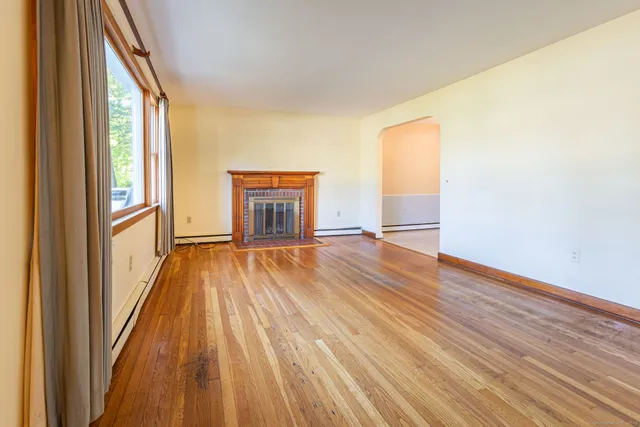 a view of empty room with wooden floor and fireplace
