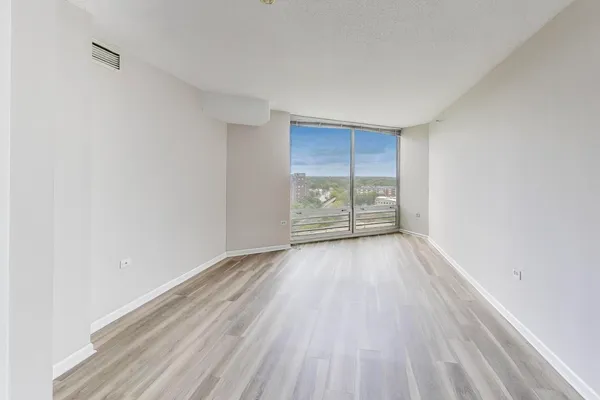 a view of an empty room with wooden floor and closet