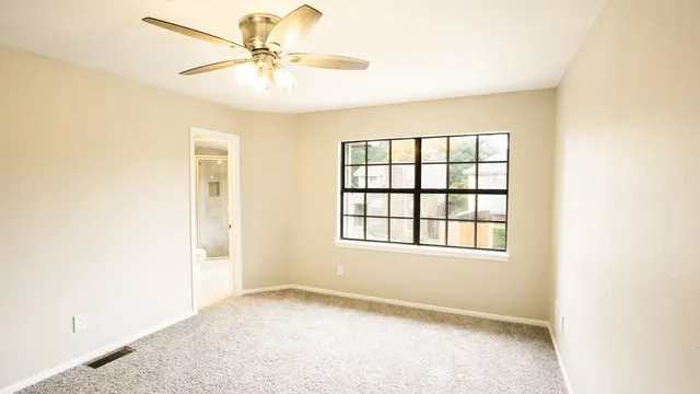 an empty room with a window and a fan