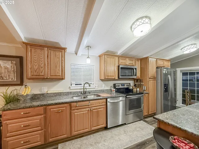 a kitchen with stainless steel appliances granite countertop a sink stove and refrigerator