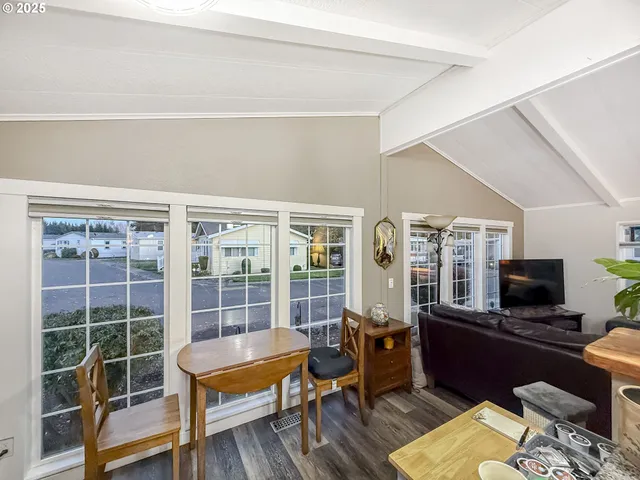 a living room with furniture floor to ceiling window hardwood floor and a flat screen tv