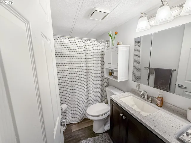a bathroom with a granite countertop sink toilet a mirror a vanity and shower