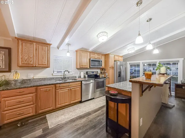 a kitchen with stainless steel appliances granite countertop a stove refrigerator sink and microwave