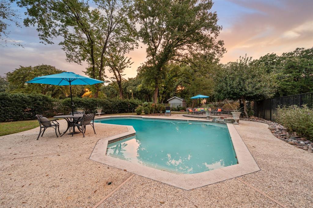 a view of a swimming pool with lawn chairs under an umbrella