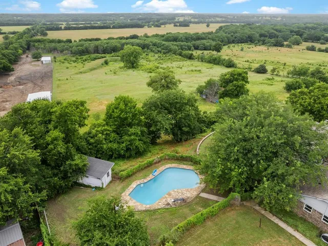 an aerial view of residential houses with outdoor space and trees all around