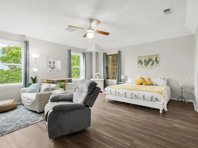 a large bedroom with a bed and wooden floor