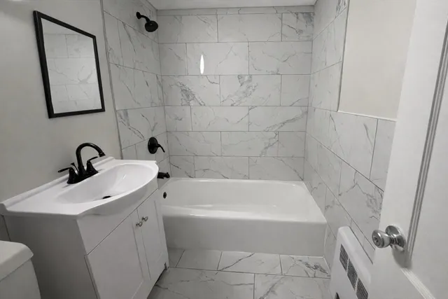 a white bath tub sitting next to a white sink and vanity