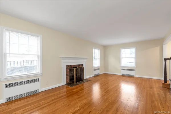 an empty room with wooden floor fireplace and windows