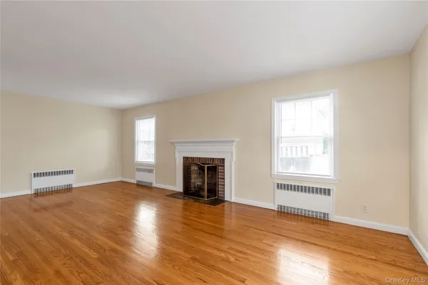 an empty room with wooden floor fireplace and windows