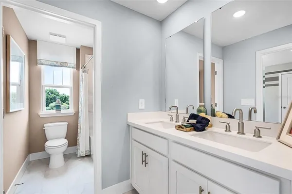 a bathroom with a double vanity sink toilet and a mirror
