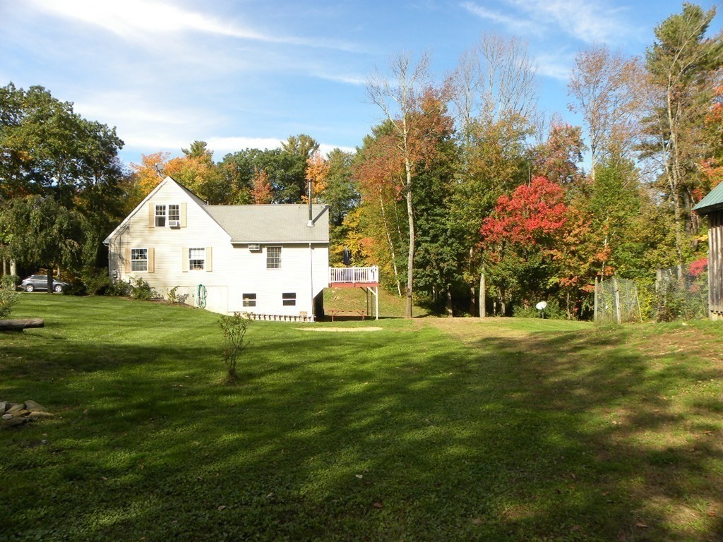 360 Coldbrook Road Oakham, MA 01068 - Photo 8 of 28 a view of a white house with a yard and large tree