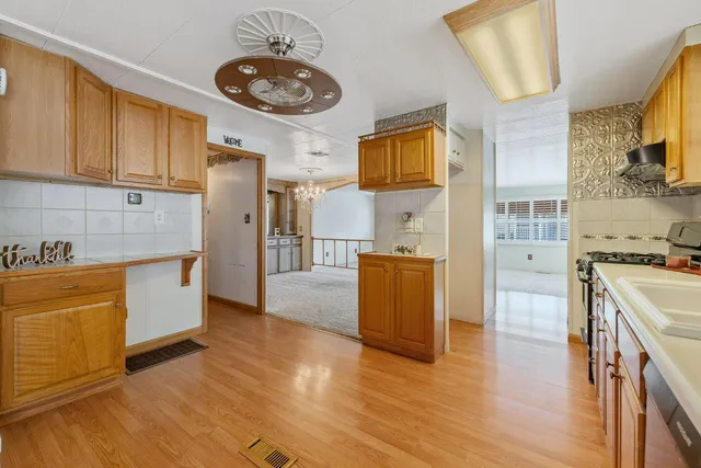a large kitchen with stainless steel appliances granite countertop a stove and a wooden floors