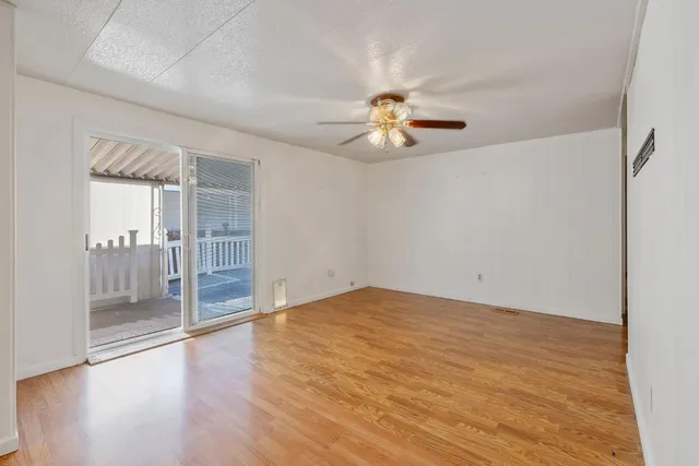 an empty room with wooden floor and chandelier fan