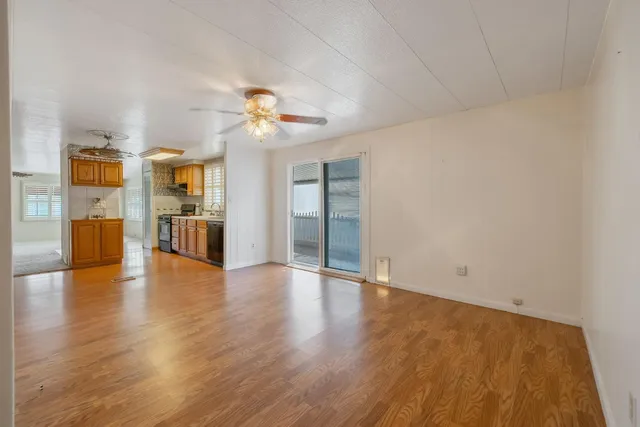 an empty room with wooden floor and a kitchen