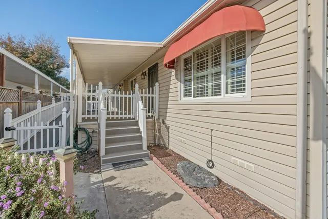 a view of a house with a small yard and wooden floor and fence