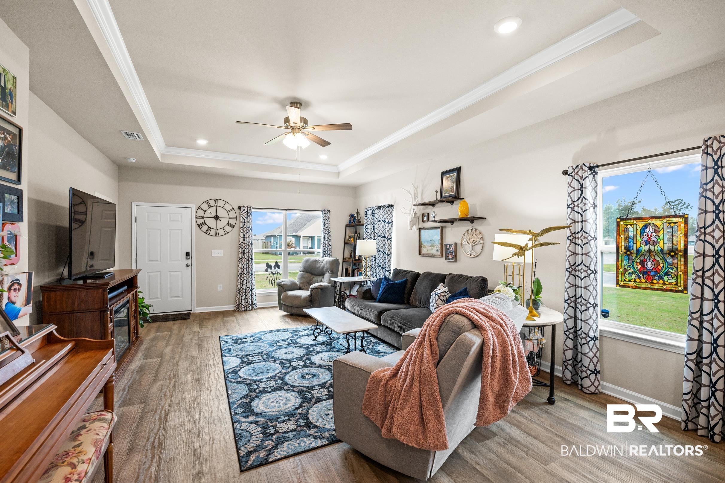 24139 Veranda Circle Elberta, AL 36530 - Photo 4 of 40 Living area with a raised ceiling, ornamental molding, wood finished floors, baseboards, and ceiling fan