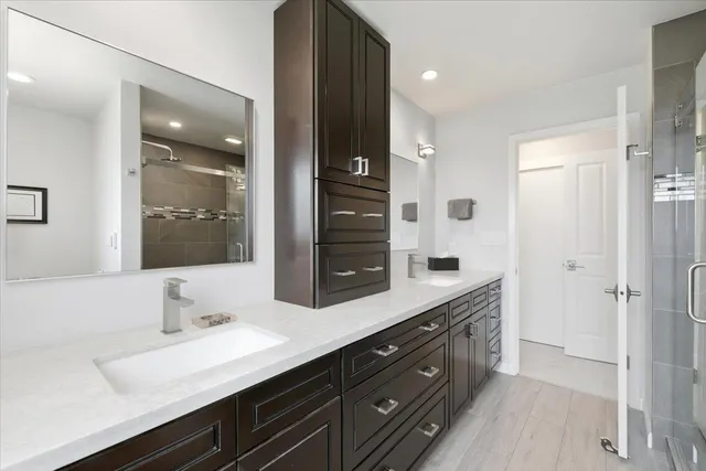a bathroom with a double vanity sink a large mirror and shower