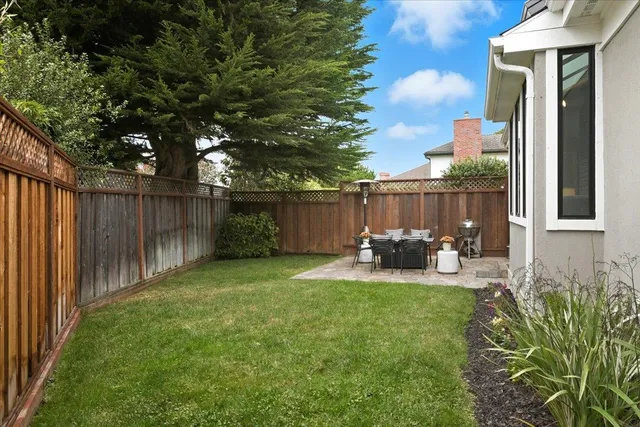 a view of backyard with table and chairs and wooden fence