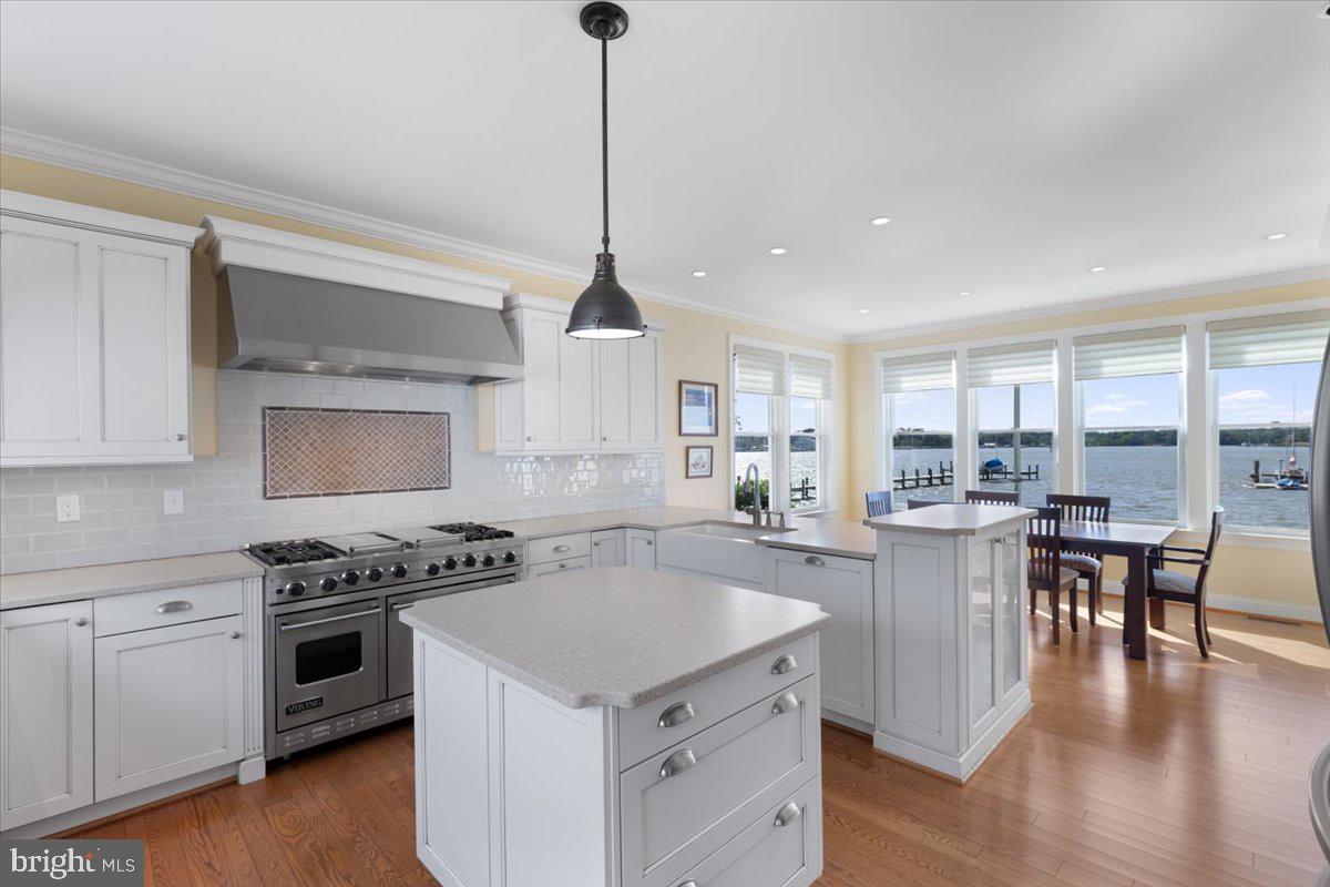 1100 Steamboat Road Shady Side, MD 20764 - Photo 13 of 81 a kitchen with a stove a sink a kitchen island with wooden floor and cabinets