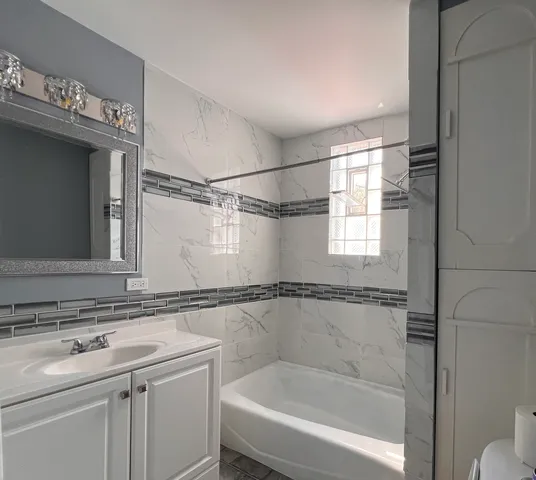 a bathroom with a sink and mirror with bathtub