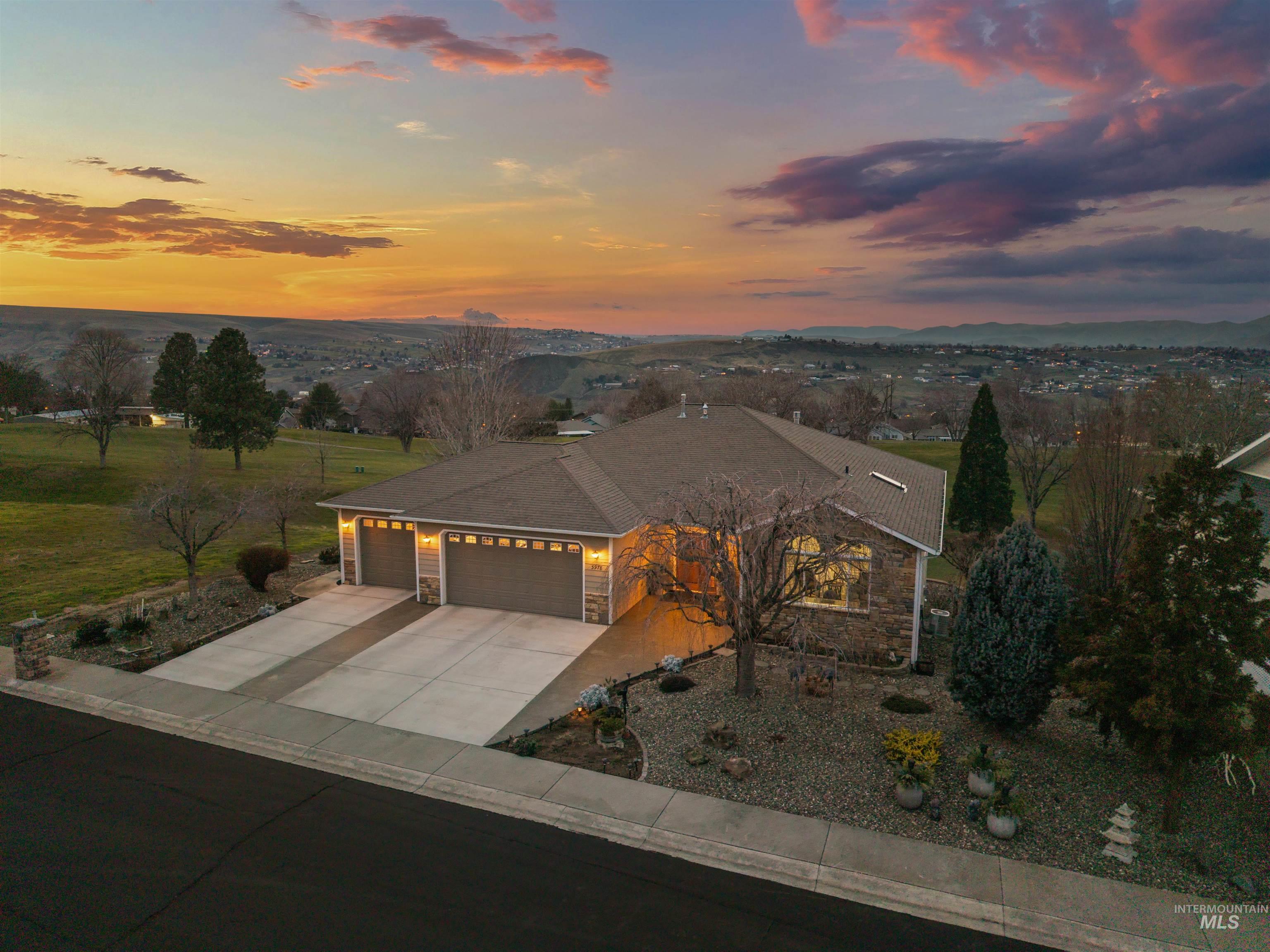 View of front of property featuring a garage, stone siding, and concrete driveway