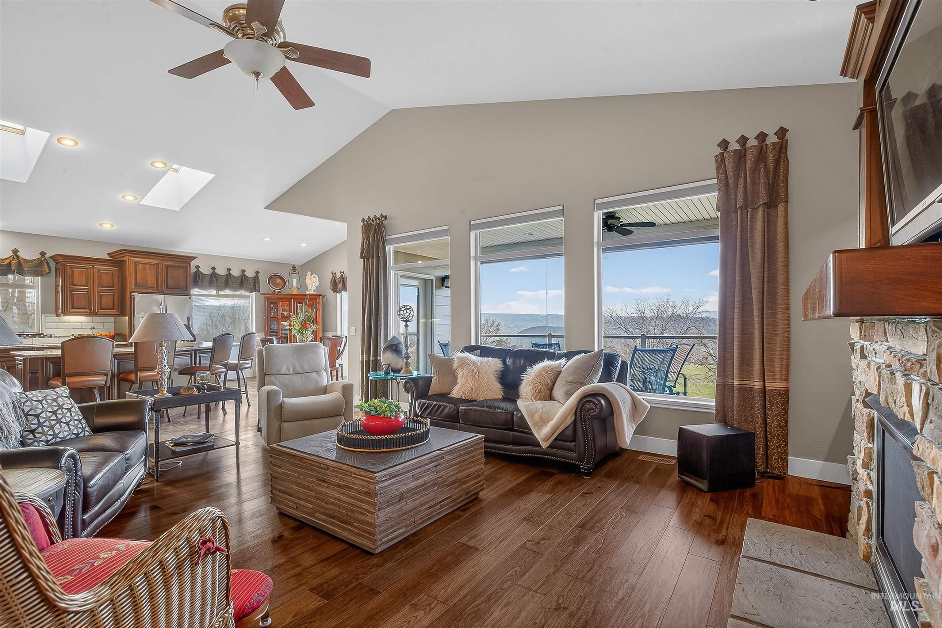 3978 Foothill Drive Lewiston, ID 83501 - Photo 11 of 40 Living area featuring a stone fireplace, dark wood finished floors, a ceiling fan, high vaulted ceiling, and a skylight