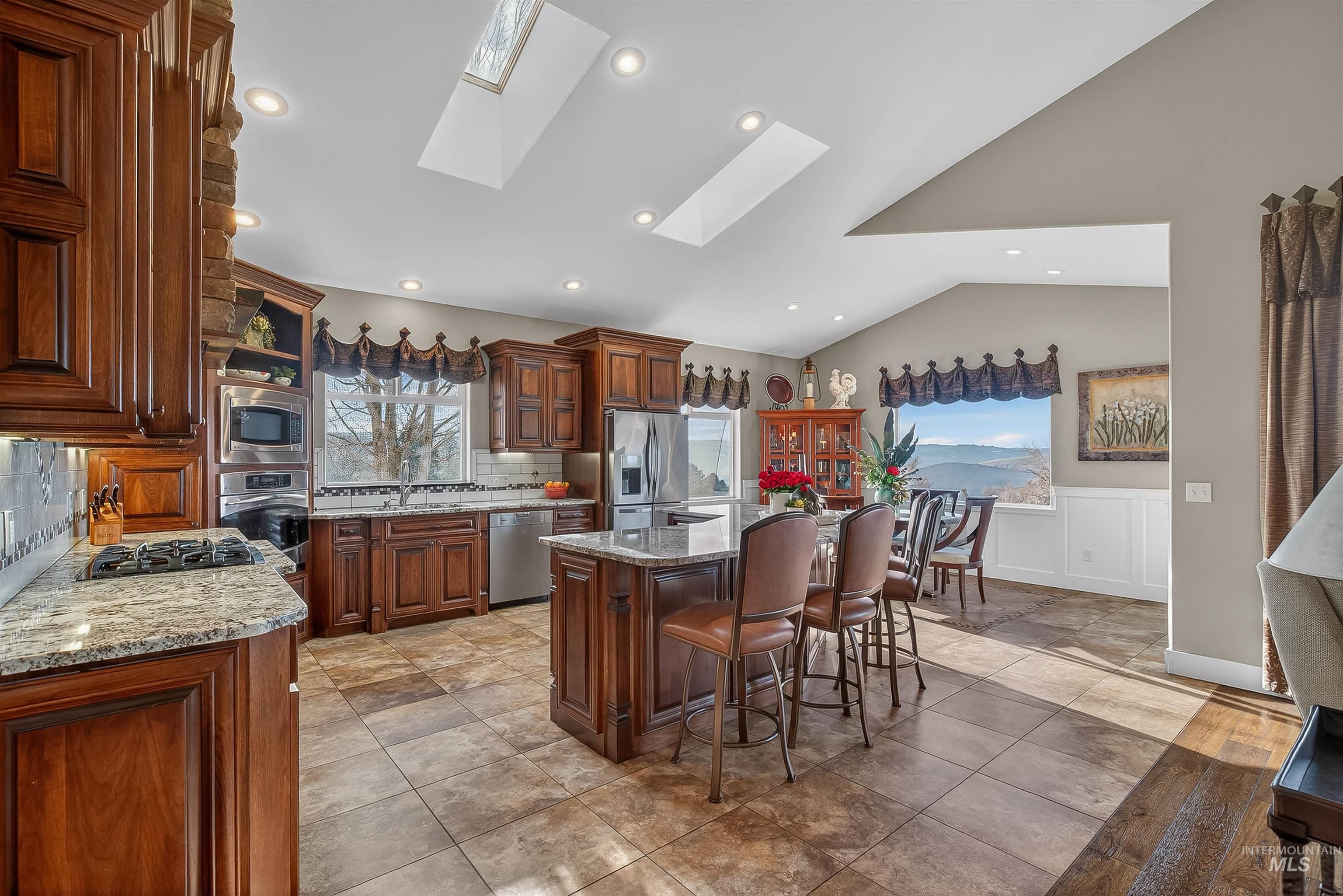 3978 Foothill Drive Lewiston, ID 83501 - Photo 16 of 40 Kitchen with light stone counters, backsplash, a skylight, appliances with stainless steel finishes, and lofted ceiling
